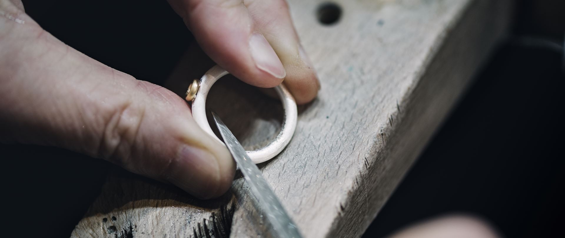 Omarbetning av ring där guldsmed filar och anpassar smycket för hand i verkstaden